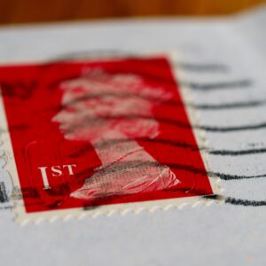 Detailed view of a red first-class postage stamp with a visible postmark.